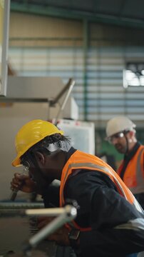 Hard Hat Heroes: Two industrial workers in hard hats and safety vests focus on their tasks within a factory setting, embodying the dedication and precision of the modern workforce.