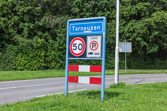 Terneuzen, Netherlands. Blue city limit entrance signpost for Terneuzen alongside a 50 km speed limit zone and a no parking restriction sign for trucks and buses.