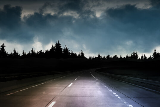 Empty highway at night under storm clouds and dark sky