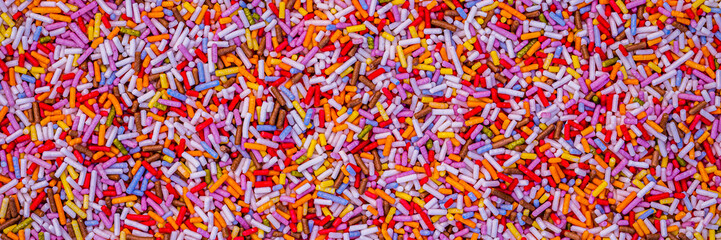 Fototapeta premium Colorful sprinkles cover a flat surface in various shapes and sizes during a baking event