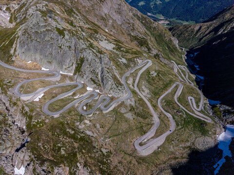 Aerial view of the winding Tremola road with its iconic serpentine curves carved into the steep rocky mountain slopes of the Gotthard Pass in Airolo, Ticino, Switzerland.