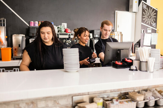 Cafe staff processing an order at the counter with POS