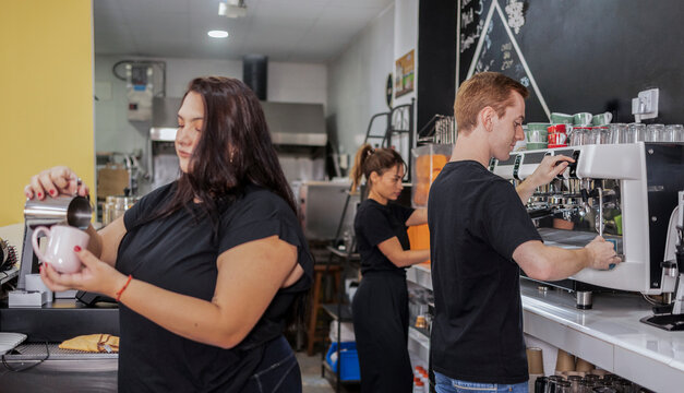 Baristas preparing coffee and espresso drinks in busy cafe