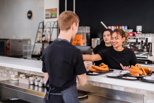 Barista team serving coffee with churros and porras