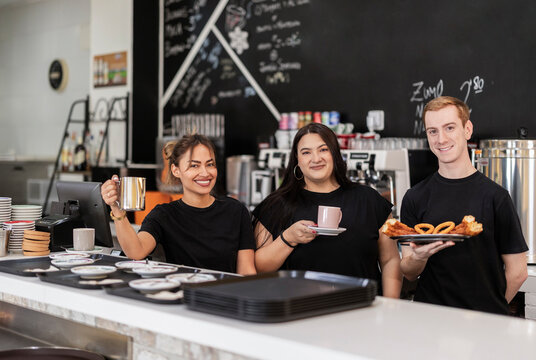Cafe staff smiling behind counter with coffee and churros