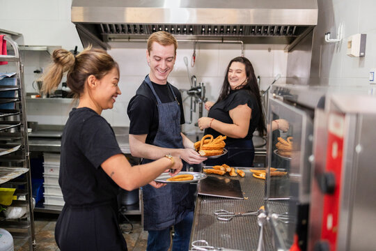 Restaurant kitchen team plating fried churros at work