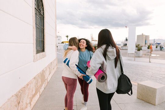 Women friends meeting outdoors with yoga mats for practice