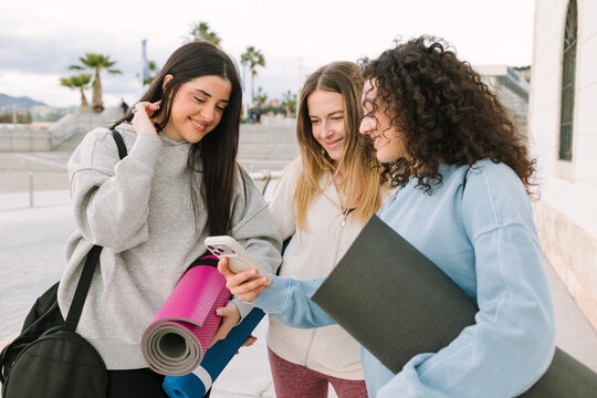 Three women friends meet outdoors for a yoga session