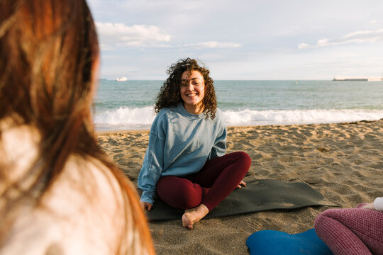 Women friends practising beach yoga and mindful breathing