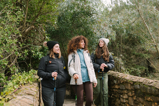 Winter mountain hike with friends on a forest trail bridge