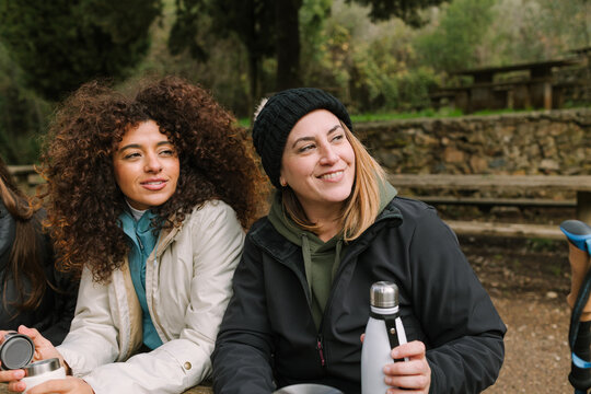 Winter mountain hike break with friends sharing warm drinks