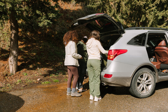Hikers packing gear in SUV at winter mountain trailhead