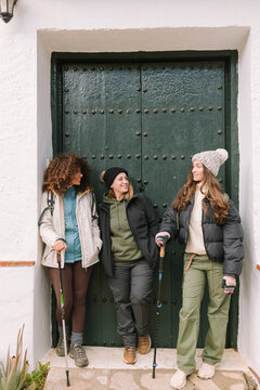 Three female hikers chatting by green door in winter