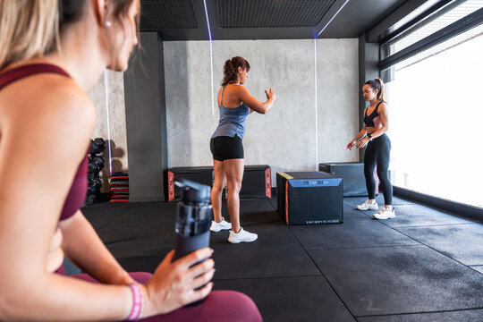 Women training in gym with coach instruction and plyo box