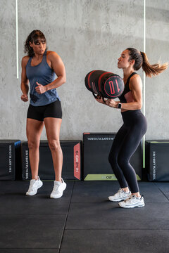 Female coach guiding athlete during sandbag strength lift