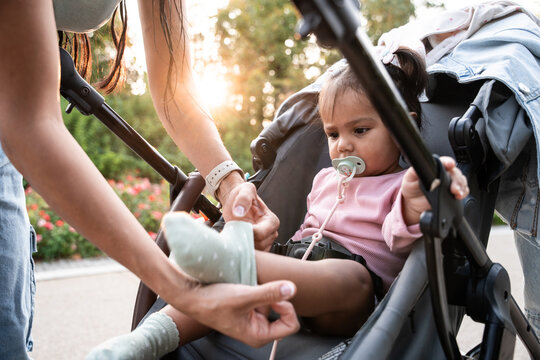 Mother adjusting baby shoe in stroller outdoors