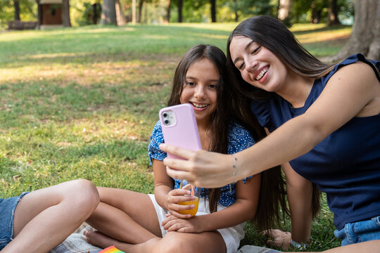 Sibling girls taking a selfie on a picnic in the park