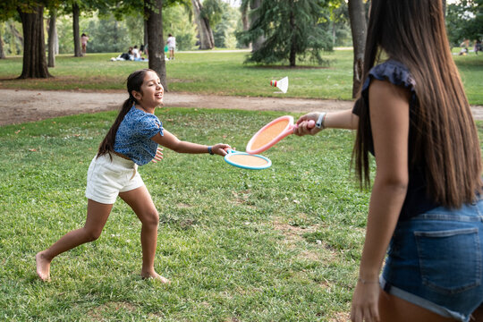 Sisters playing paddle ball game together in summer park