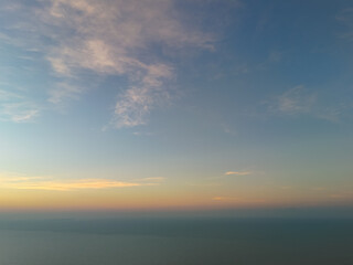 Fototapeta premium Aerial Peaceful coastal sunrise seascape with calm ocean horizon and soft pastel morning sky