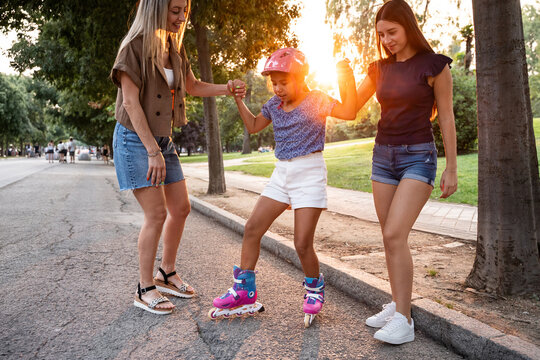 Mother with two daughters helping child roller skate