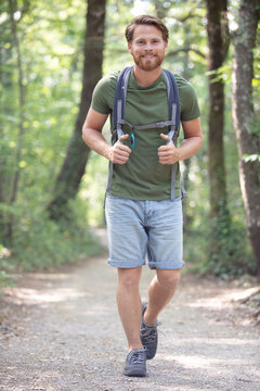 man wearing a backpack is walking in the woods