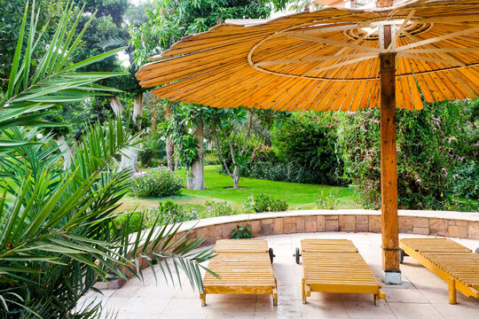 Garden lounge chairs beneath a yellow umbrella