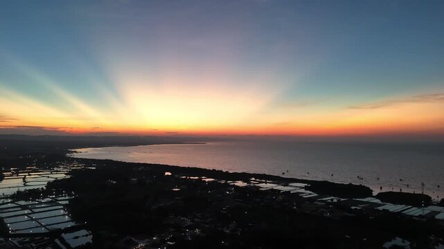 Cinematic Aerial Drone Shot of Majestic Sunrise with Crepuscular Rays over Coastline and Aquaculture Ponds