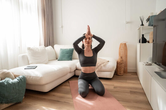 Young woman practicing yoga at home in bright living room