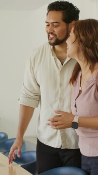 Vertical video: Extending off-frame staff handing keys to couple at wood counter, finalizing lease