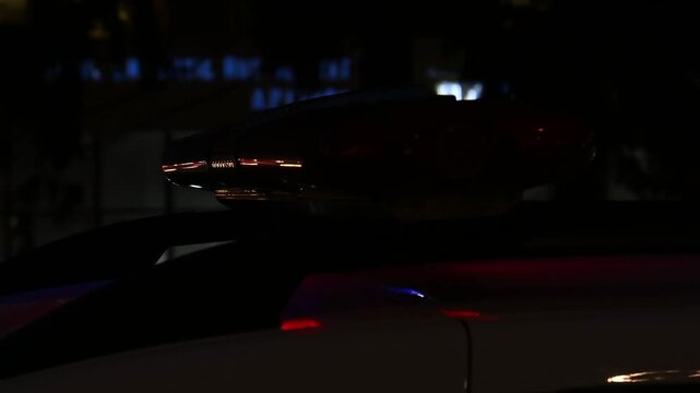 Police patrol car with flashing red and blue lights on roof at night, close up, motion footage.