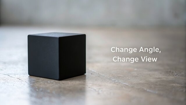 Minimalist black cube on textured surface with message about perspective and viewpoint change in modern design and architecture