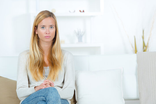 portrait of serious young woman sat alone on sofa