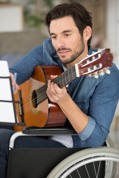 focused musician on a wheelchair playing guitar