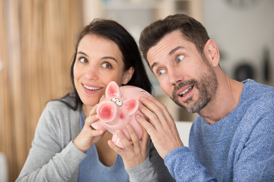 young happy couple smile and holding piggy bank