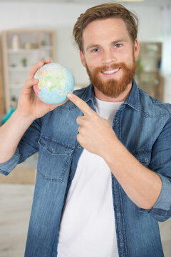 smiling man holding a globe and searching locations