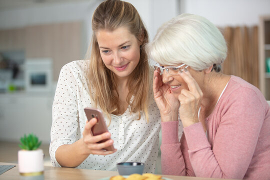 pleasant smiling mother and daughter using cell phone