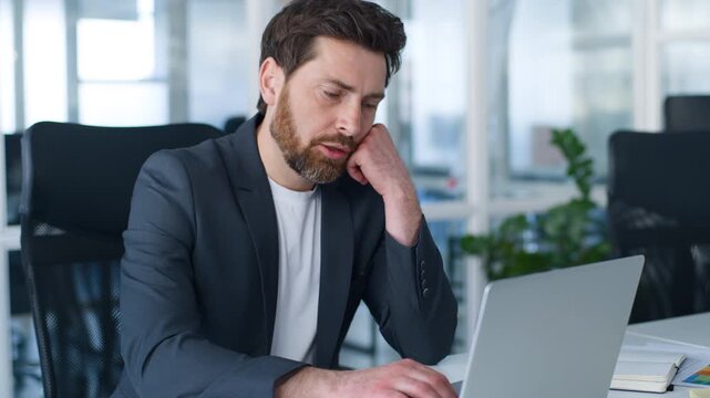 Sleepy Caucasian business man typing laptop feeling boredom burnout middle-aged businessman working with computer boring task unproductive work online in office company mature male tired with chatting