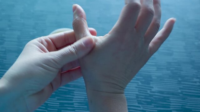 Woman applying soothing cream on painful thumb after computer work