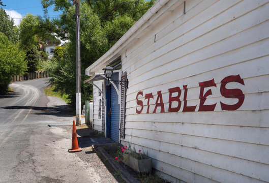 Wooden shed with text : Stables. Horse stable at Puhoi in rural landscape with country road