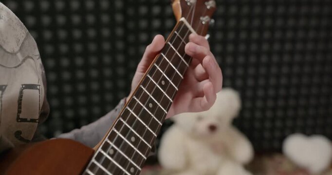 Boy Play Music on Ukulele Instrument in Home Studio. 4K 10-bit