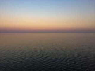 Obraz premium Serene ocean view at sunset with calm waters and gradient sky 