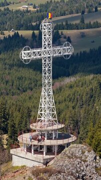 Aerial drone view of the large metal cross and Romanian flag near Acoperamantul Maicii Domnului Monastery in Dorna Arini. Vertical