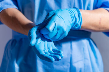 Obraz na płótnie Canvas Healthcare professional putting on blue medical gloves on white background with copy space