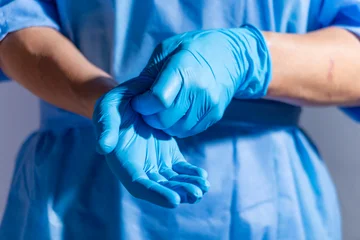 Healthcare professional putting on blue medical gloves on white background with copy space © Mikhailov Studio