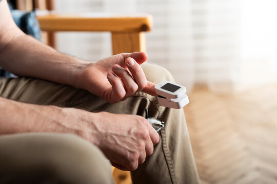 Caucasian middle aged man using pulse oximeter at home