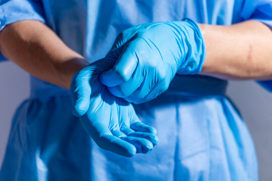Healthcare professional putting on blue medical gloves on white background with copy space