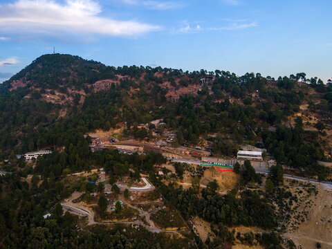 Aerial view of Dino Valley theme park nestled in the Margalla Hills with winding roads and dense green trees under a clear sky Islamabad, Islamabad Capital Ter, Pakistan.