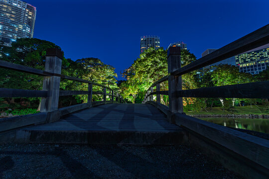 Illuminated Otsutai Bridge and Shiodome skyscrapers at night in Hamarikyu Gardens October 2023