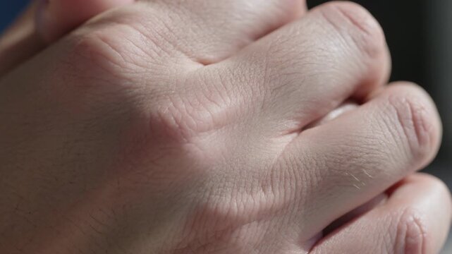 Camera capturing adult hand tightening fingers in room interior, showing knuckle detail
