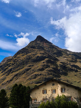 Traditional Alpine House Beneath a Dramatic Mountain Peak in the Swiss Alps
